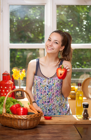 Beautiful young brunette woman preparing healthy food in the kitchen.の写真素材