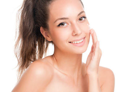 Portrait of a brunette beauty applying moisturizer on her skin.の写真素材