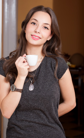 Portrait of a gorgeous young brunette woman holding cup of coffee.の写真素材