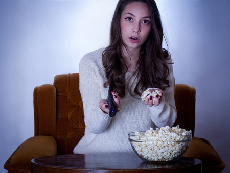 Portrait of young brunette in front of the television.の写真素材