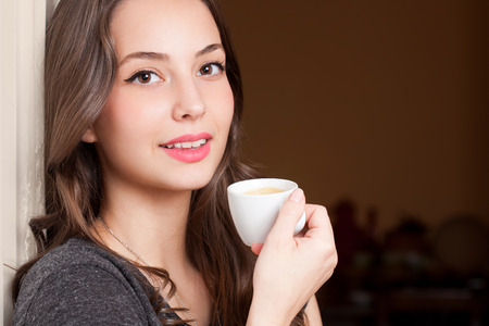Portrait of a gorgeous young brunette woman holding cup of coffee.の写真素材