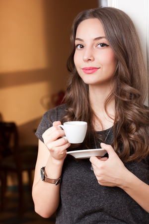 Portrait of a gorgeous young brunette woman holding cup of coffee.の写真素材