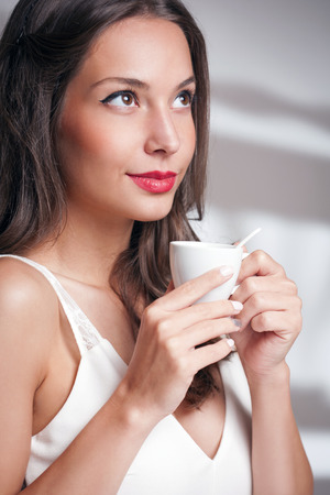 Elegant gorgeous young brunette woman with a cup of gourmet coffee.の写真素材