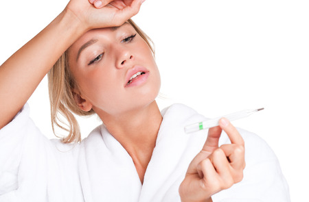 Portrait of a worried young blond beauty checking her temperature.