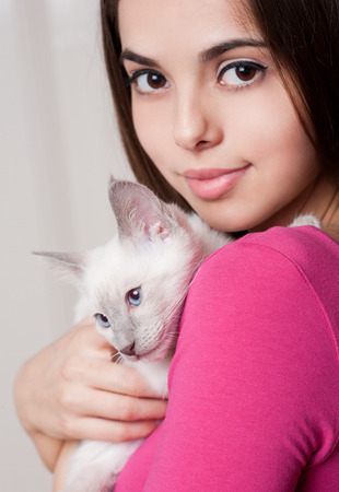 Portrait of a beautiful brunette holding a cute kitten.の写真素材