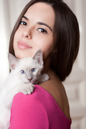 Gorgeous young brunette holding sweet young siamese kitten.の写真素材