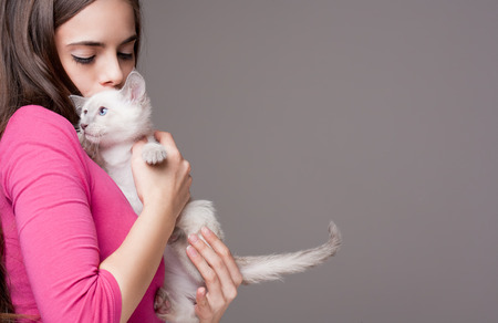 Portrait of a beautiful brunette holding a cute kitten.の写真素材