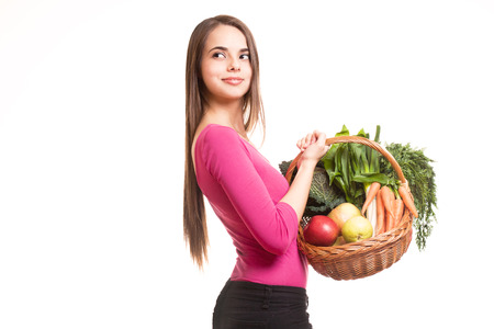 Beautiful young brunette woman holding basket of fruits and vegetables.の写真素材