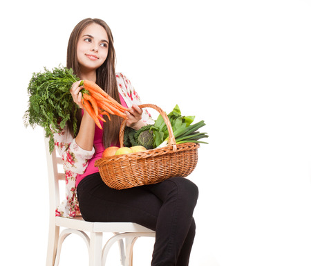 Beautiful young brunette woman holding basket of fruits and vegetables.の写真素材