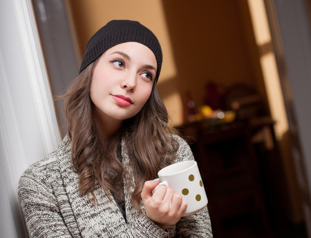 Portrait of a gorgeous young brunette woman relaxing with mug of hot beverage.の写真素材