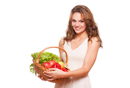 Beautiful young brunette woman posing with basket of fresh vegetables.の写真素材