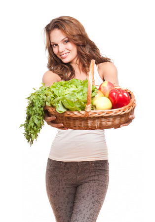 Beautiful young brunette woman posing with basket of fresh vegetables.の写真素材