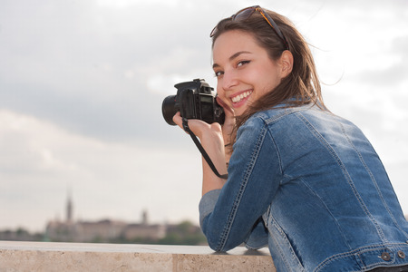 Beautiful happy young brunette taking photographs.の写真素材