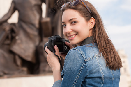 Beautiful happy young brunette taking photographs.の写真素材