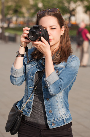 Beautiful happy young brunette taking photographs.の写真素材