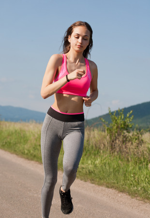 Fit and agile young brunette woman running outdoors in the sunshine.の写真素材