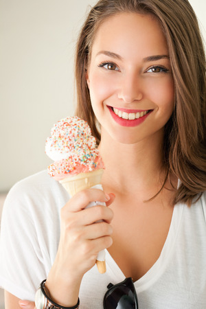 Portrait of a gorgeous happy brunette woman having summer ice cream fun.の写真素材