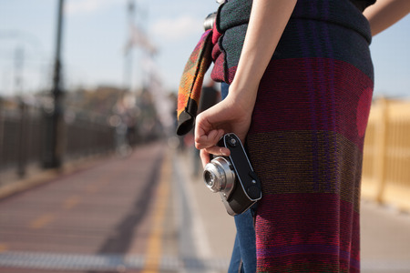 Young photographer strolling the sunlit city streets with her camera.の写真素材