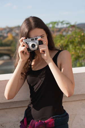 Young photographer strolling the sunlit city streets with her camera.の写真素材