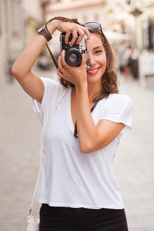 Portrait of a young brunette tourist woman taking photo.の写真素材