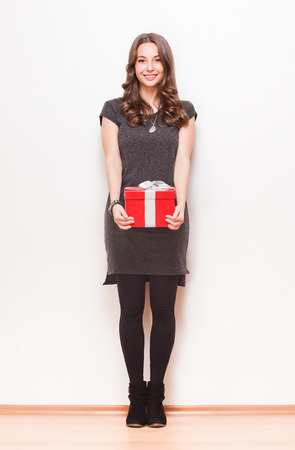 Portrait of a gorgeous young brunette woman with shiny red gift box.の写真素材