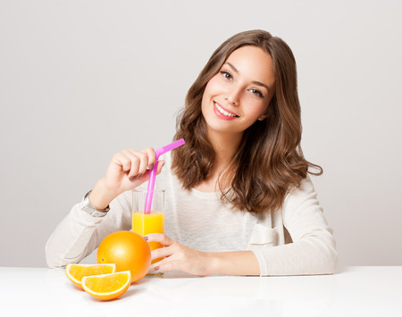 Portrait of a beautiful young brunette woman having orange juice.の写真素材