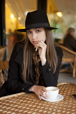 Outdoors portrait of a beautiful young brunette woman having coffee.の写真素材