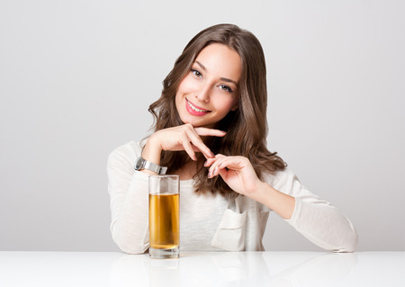 Studio portrait of a happy young brunette woman with glass of apple juice.の写真素材