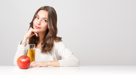 Portrait of a healthy young brunette beauty with glass of apple juice.の写真素材