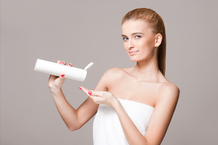 Portrait of a gorgeous young blond woman using moisturizer.の写真素材
