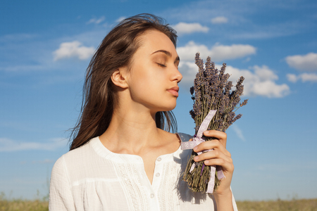Portrait of a young brunette beauty enjoying the scent of lavender outdoors.の写真素材
