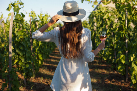 Portrait of a gorgeous brunette woman having wine fun in the vineyards.の写真素材