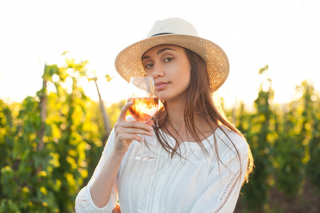 Portrait of young brunette beauty in the vineyards having wine.の写真素材