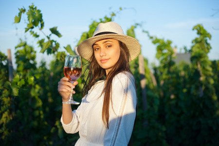 Portrait of a gorgeous brunette woman having wine fun in the vineyards.の写真素材