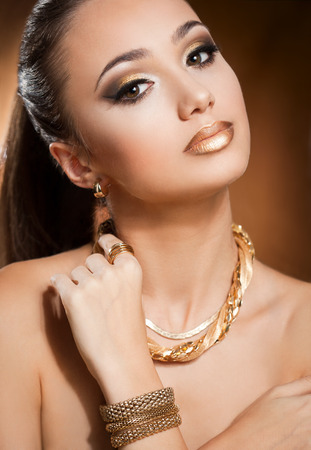 Portrait of a beautiful young brunette woman wearing gold jewelry.の写真素材