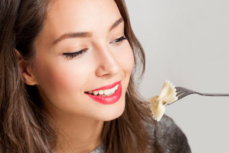 Beautiful young brunette woman eating Italian meal.の写真素材