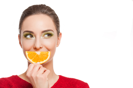 Young brunette beauty on colorful makeup holding fresh fruits full of vitamins.の写真素材