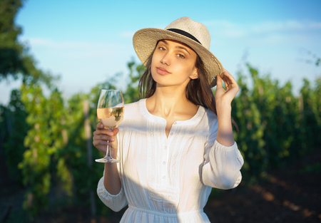 Portrait of young brunette beauty in the vineyards having wine.の写真素材