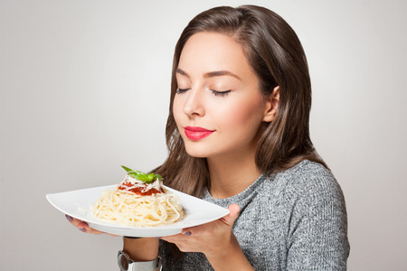 Beautiful young brunette woman eating Italian pasta.の写真素材