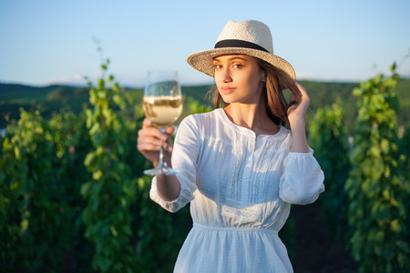 Portrait of young brunette beauty in the vineyards having wine.の写真素材