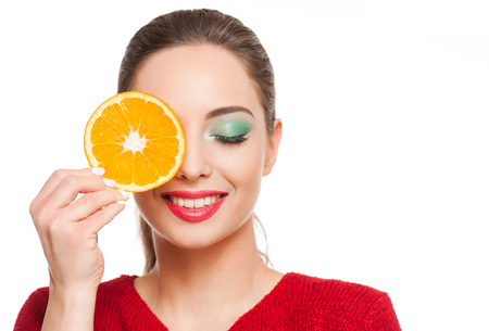Young brunette beauty on colorful makeup holding fresh fruits full of vitamins.の写真素材