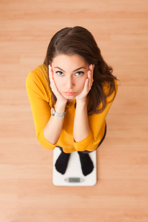 Portrait of a gorgeous young brunette woman standing on a scale.の写真素材