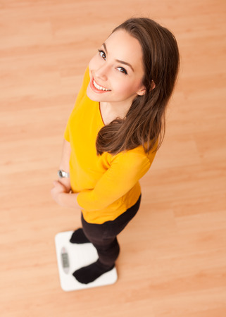 Portrait of a gorgeous young brunette woman standing on a scale.の写真素材