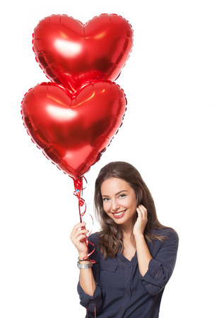 Portrait of a cute brunette with heart balloons on white background.の写真素材