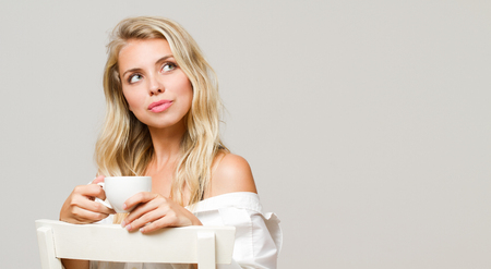 Portrait of a gorgeous blond woman drinking coffee.の写真素材