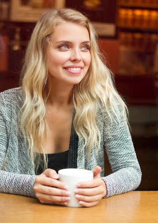 Portrait of a gorgeous blond woman drinking coffee.の写真素材