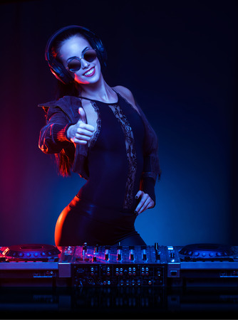 Gorgeous young female DJ in colorful stage lighting.の写真素材