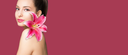 Brunette beauty in light makeup holding colorful lily flower.の写真素材