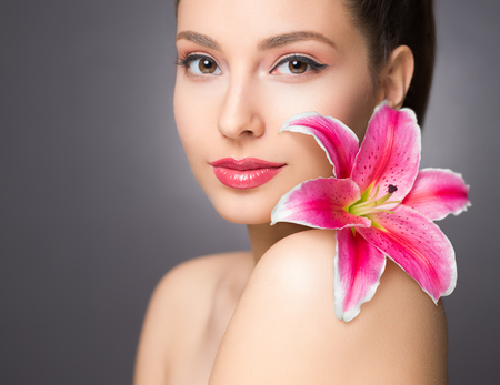 Brunette beauty in light makeup holding colorful flower.の写真素材