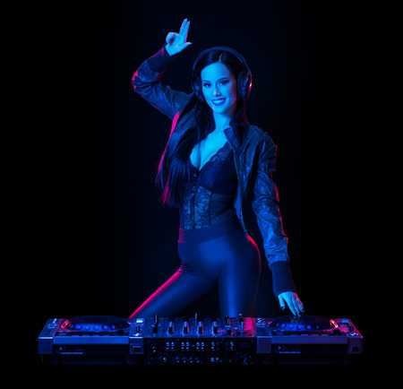 Gorgeous young female DJ in colorful stage lighting.の写真素材
